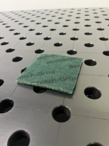 Scotchbrite pad used to clean small buildup from welding table surface